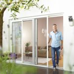 Man walking out of a sliding terrace door with installed insect screens.